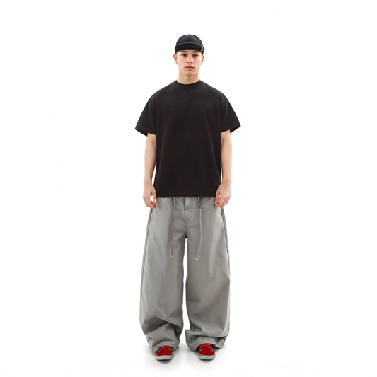 Person wearing a black t-shirt, gray pants, and red shoes on a white background