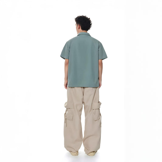 Person wearing a green shirt and beige cargo pants on a white background