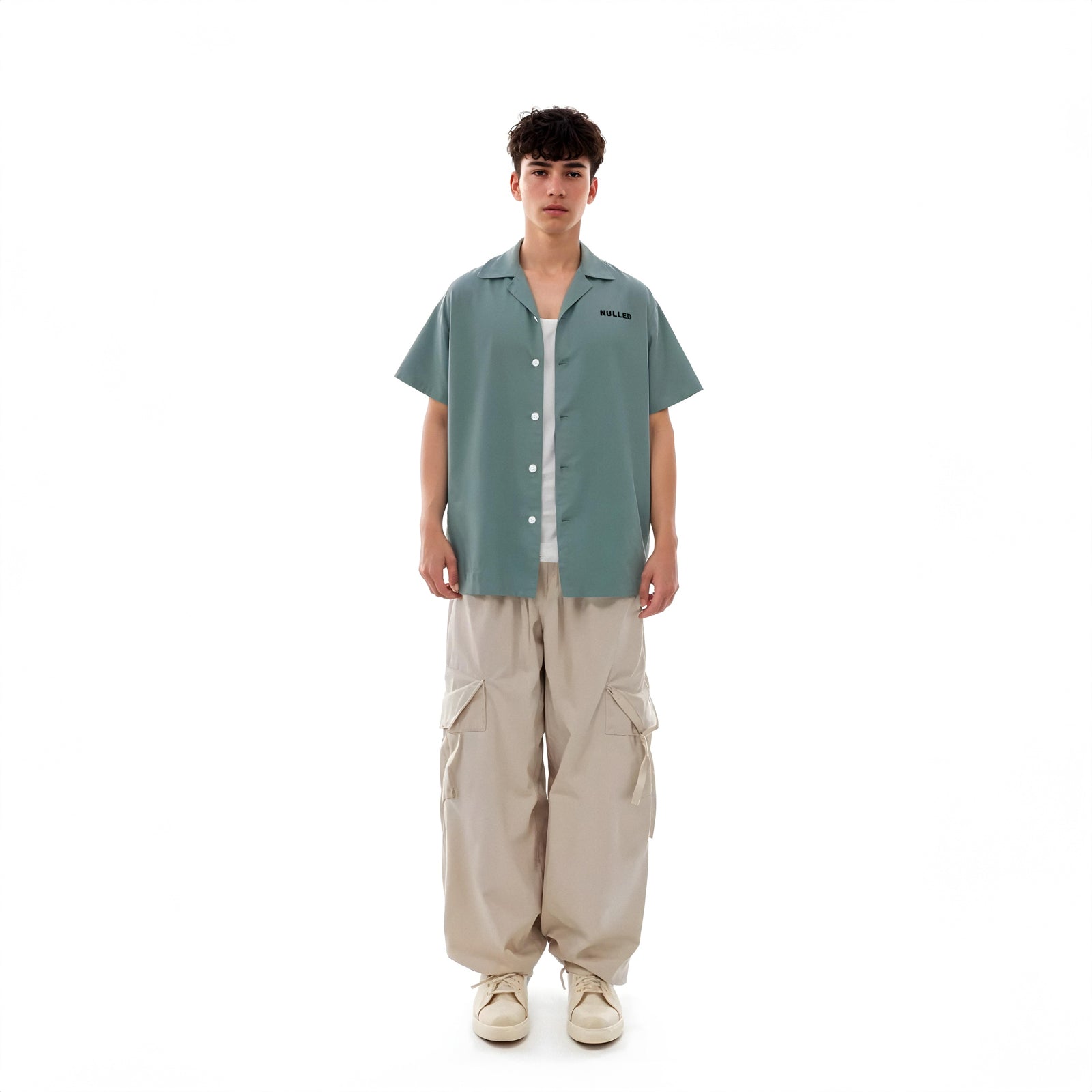 Person wearing a green shirt and beige pants on a white background
