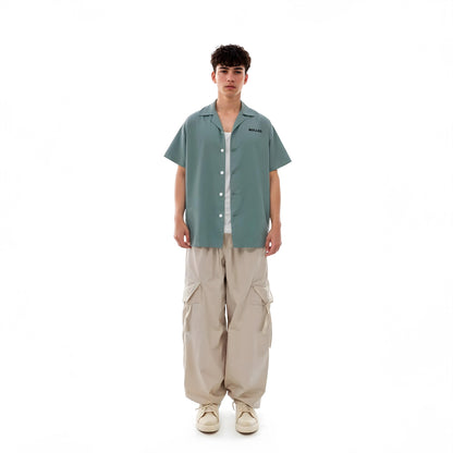 Person wearing a green shirt and beige pants on a white background