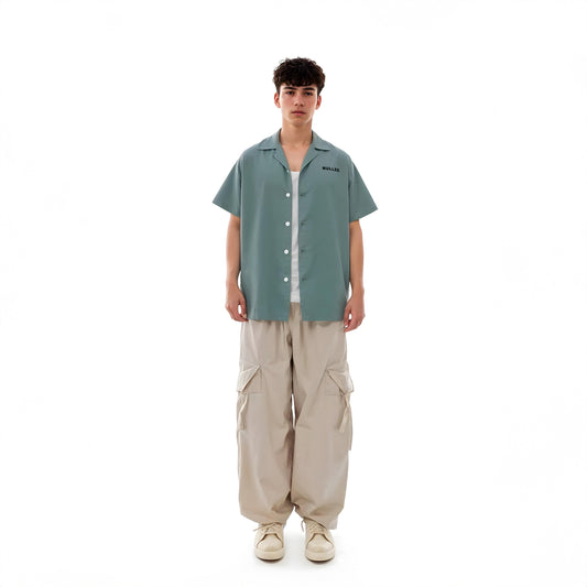 Person wearing a green shirt and beige pants on a white background
