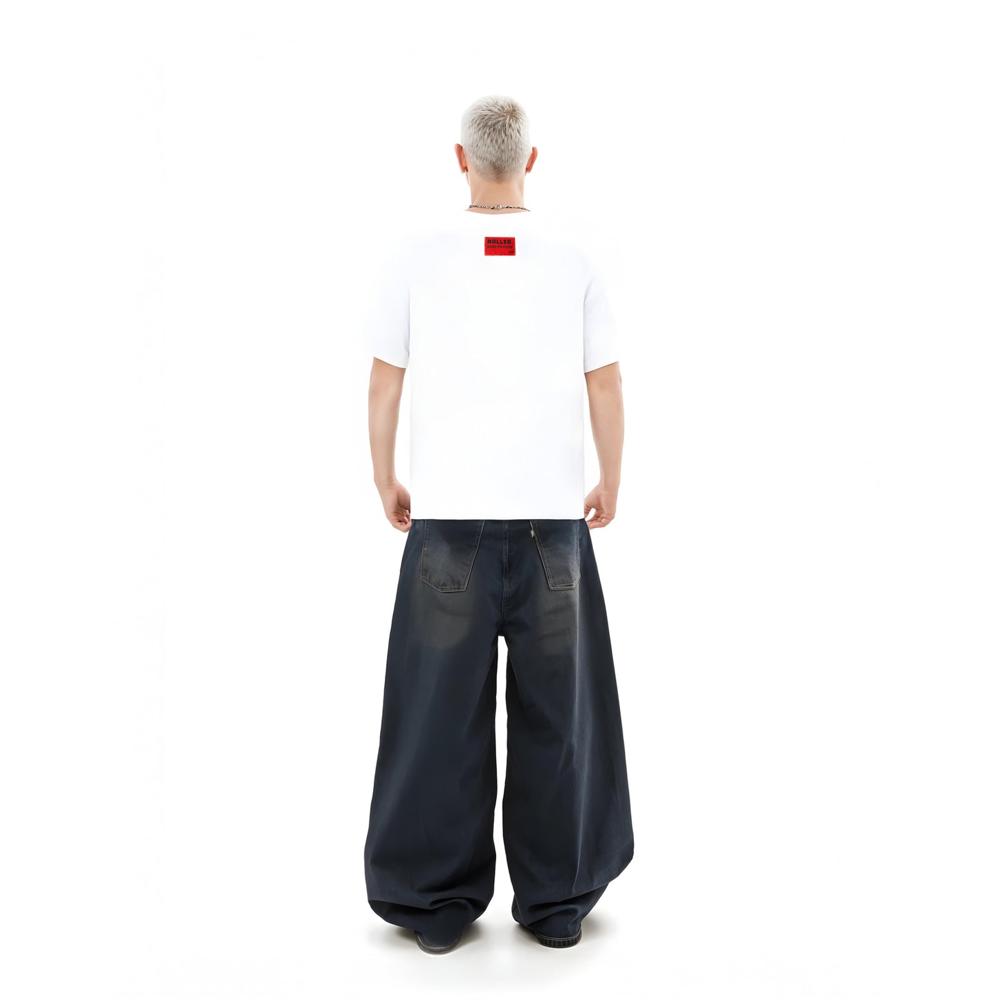 Person wearing a white t-shirt with a red logo and dark blue wide-leg pants on a white background