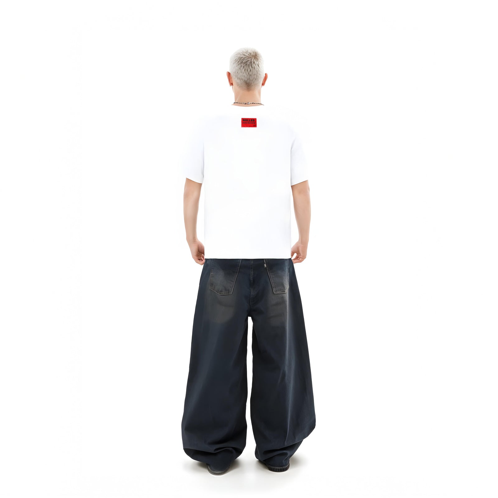 Person wearing a white t-shirt with a red logo and dark blue wide-leg pants on a white background