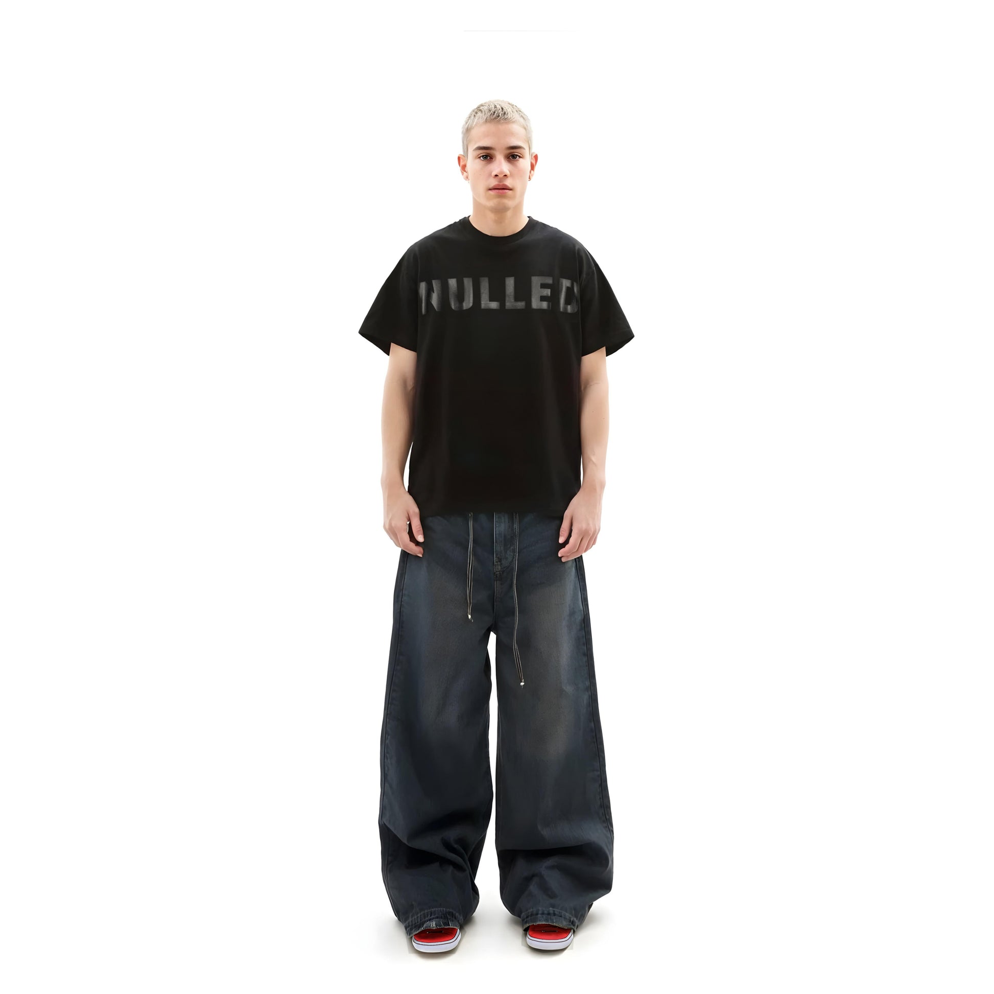 Person wearing a black t-shirt with 'HULLED' text and blue jeans on a white background