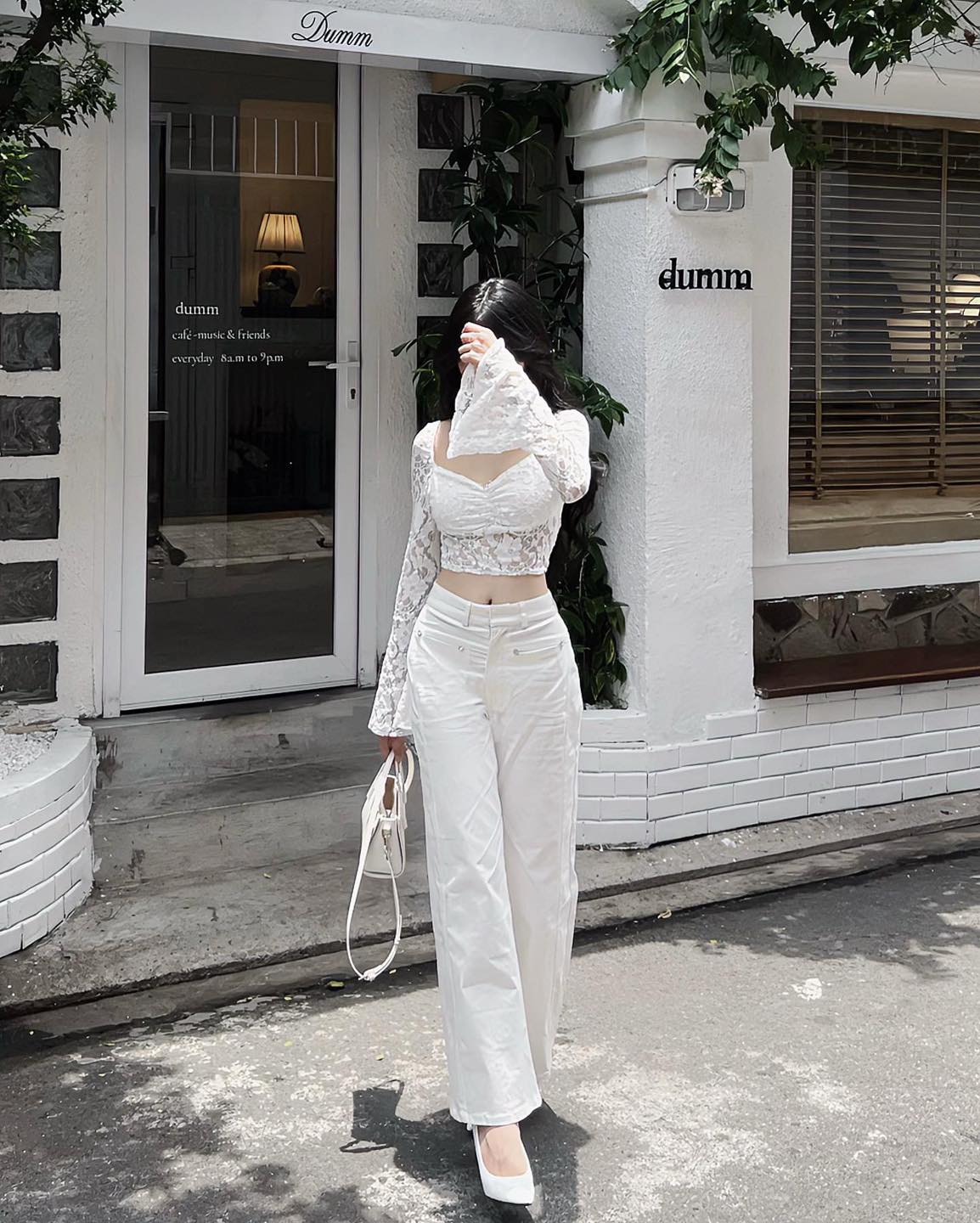 Woman in a white outfit standing outside a store named 'Dumma'.