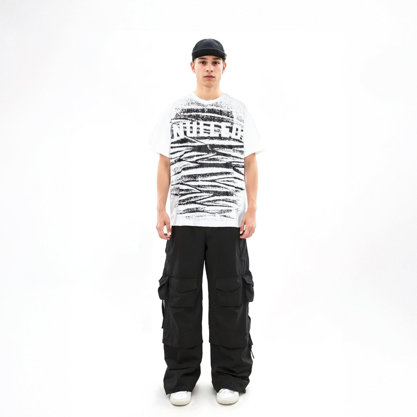 Person wearing a white t-shirt with black text and graphics, black cargo pants, and a black cap on a white background