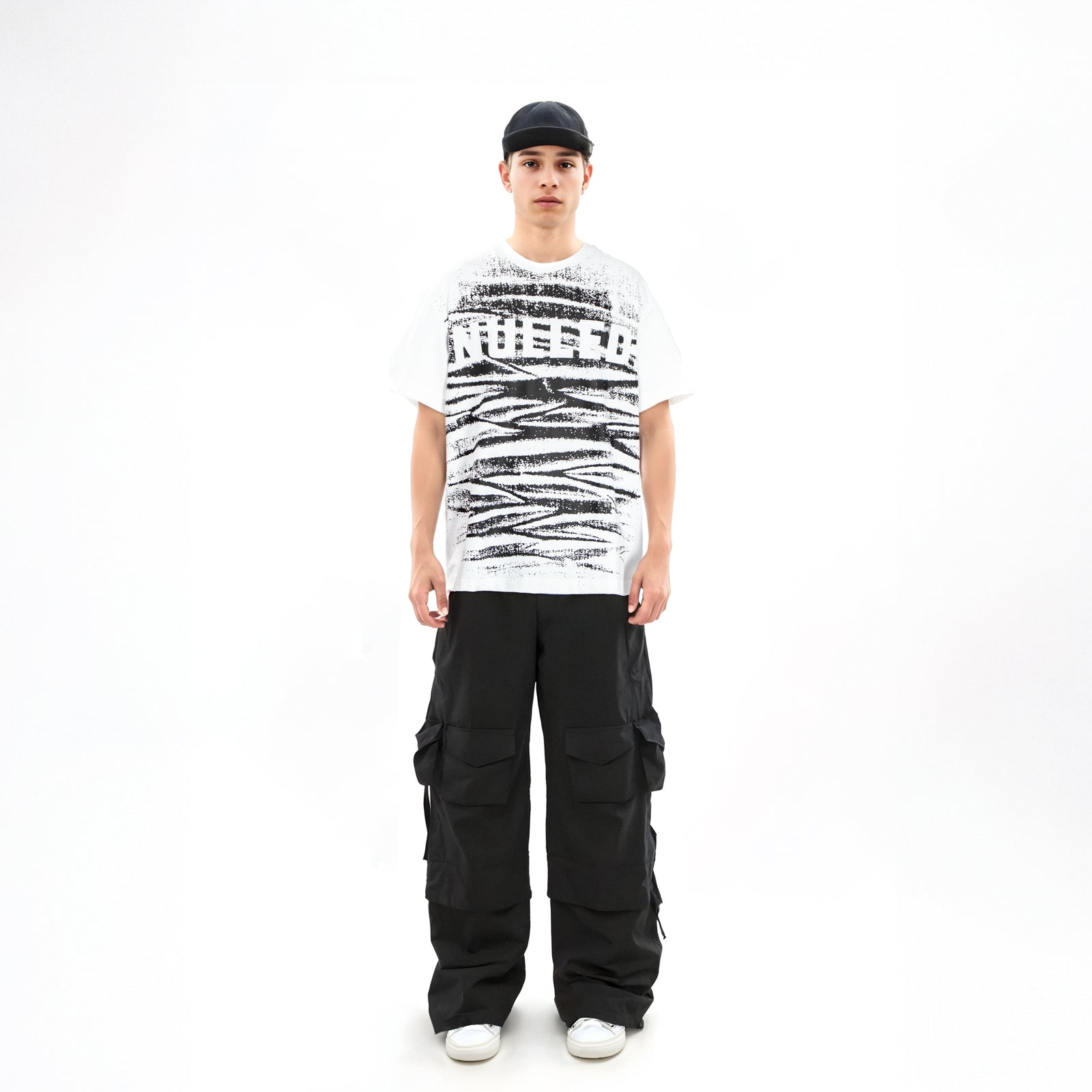 Person wearing a white t-shirt with black text and graphics, black cargo pants, and a black cap on a white background