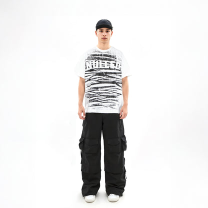 Person wearing a white t-shirt with black text and graphics, black cargo pants, and a black cap on a white background