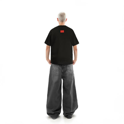 Person wearing a black t-shirt with a red logo on the back, standing against a white background