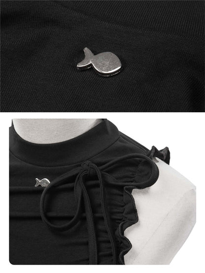 Black blouse with decorative bow and small silver fish-shaped brooch on a white background