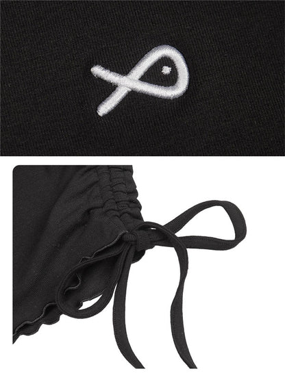 Black garment with a white embroidered symbol and a close-up of a black ribbon detail.
