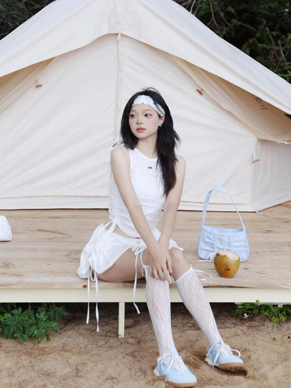 Woman in a white outfit sitting in front of a tent