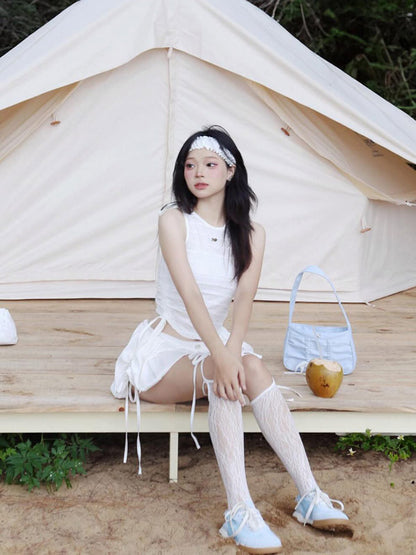 Woman in a white outfit sitting in front of a tent