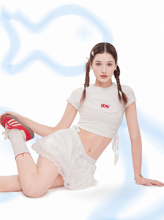 Woman in a white outfit with a logo, sitting on a white background