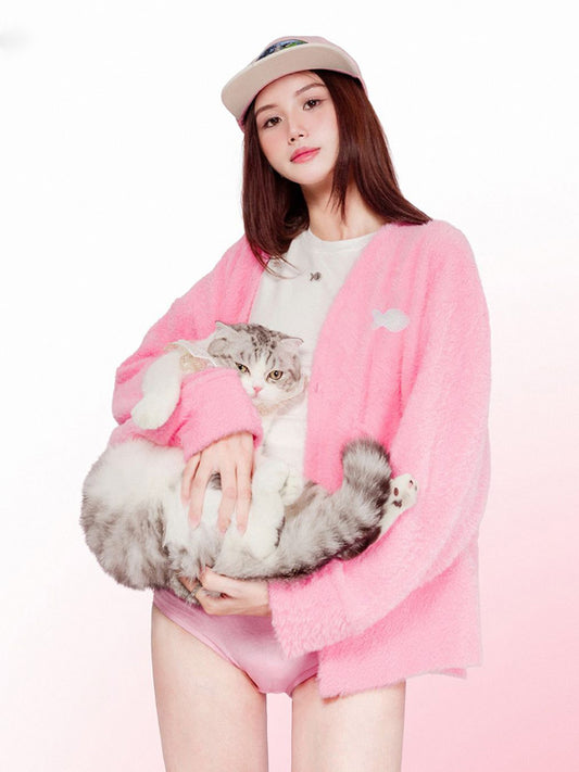 Woman in pink outfit holding a cat against a white background