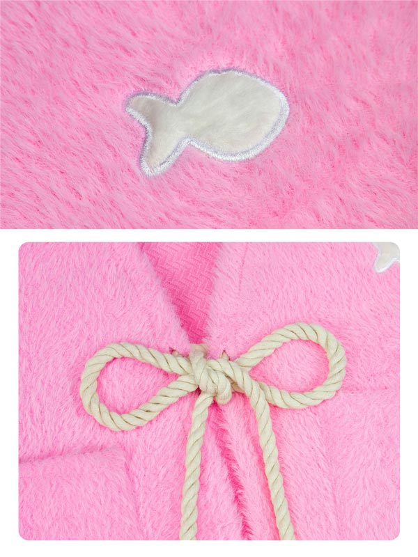 Pink fabric with a white fish-shaped patch and a beige ribbon bow on a matching pink background.