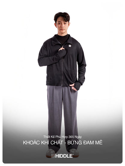 Person wearing a black jacket and gray pants with a visible brand logo on a white background