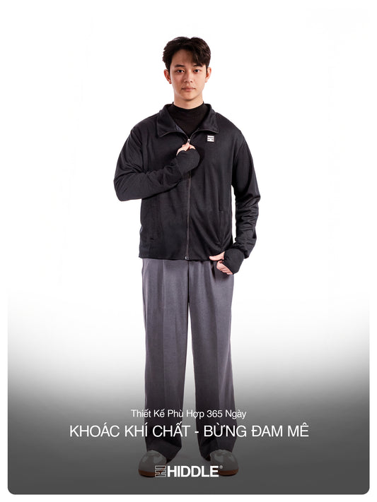 Person wearing a black jacket and gray pants with a visible brand logo on a white background