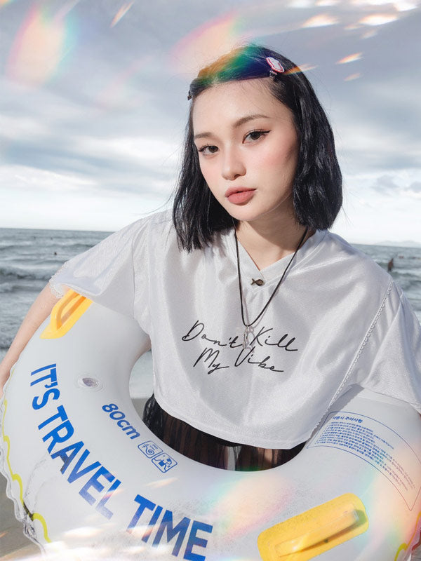 Person holding a 'It's Travel Time' inflatable ring with ocean and sky in the background