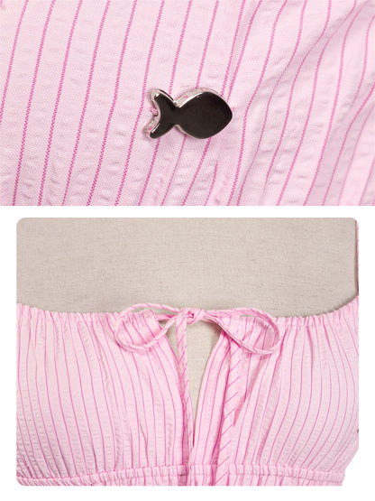 Pink striped fabric with a black fish-shaped brooch and pink shorts with a gray waistband.