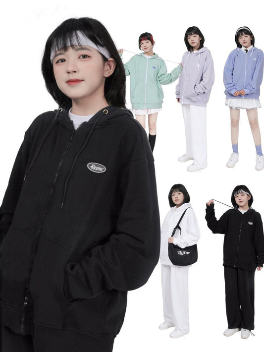 Person wearing a black hoodie with a logo, surrounded by other people in different outfits.