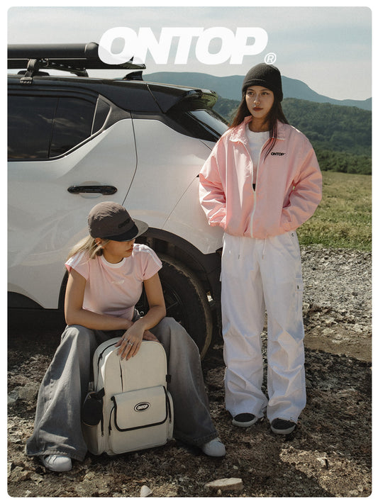 Two people in stylish outfits with a white car and 'ONTOP' branding in a mountainous landscape.