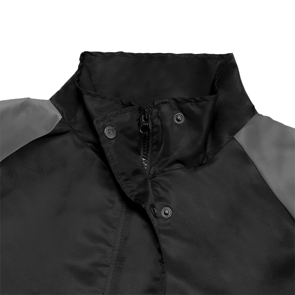 Close-up of a black and gray jacket with a zipper and button details on a white background