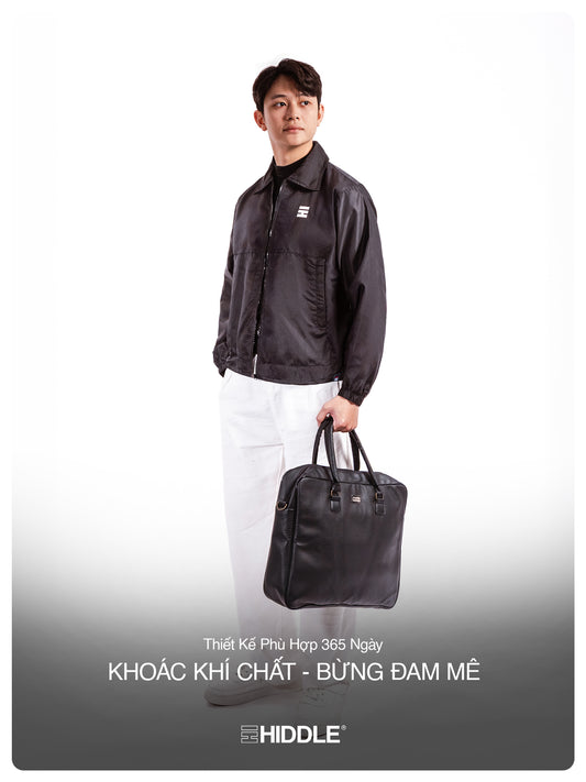 Man holding a black leather bag with Hiddle branding on a white background