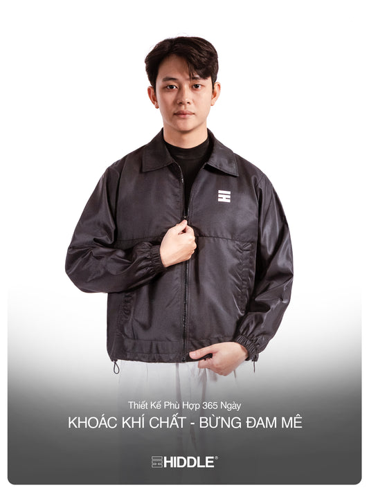 Man wearing a black jacket with a visible brand logo on a white background