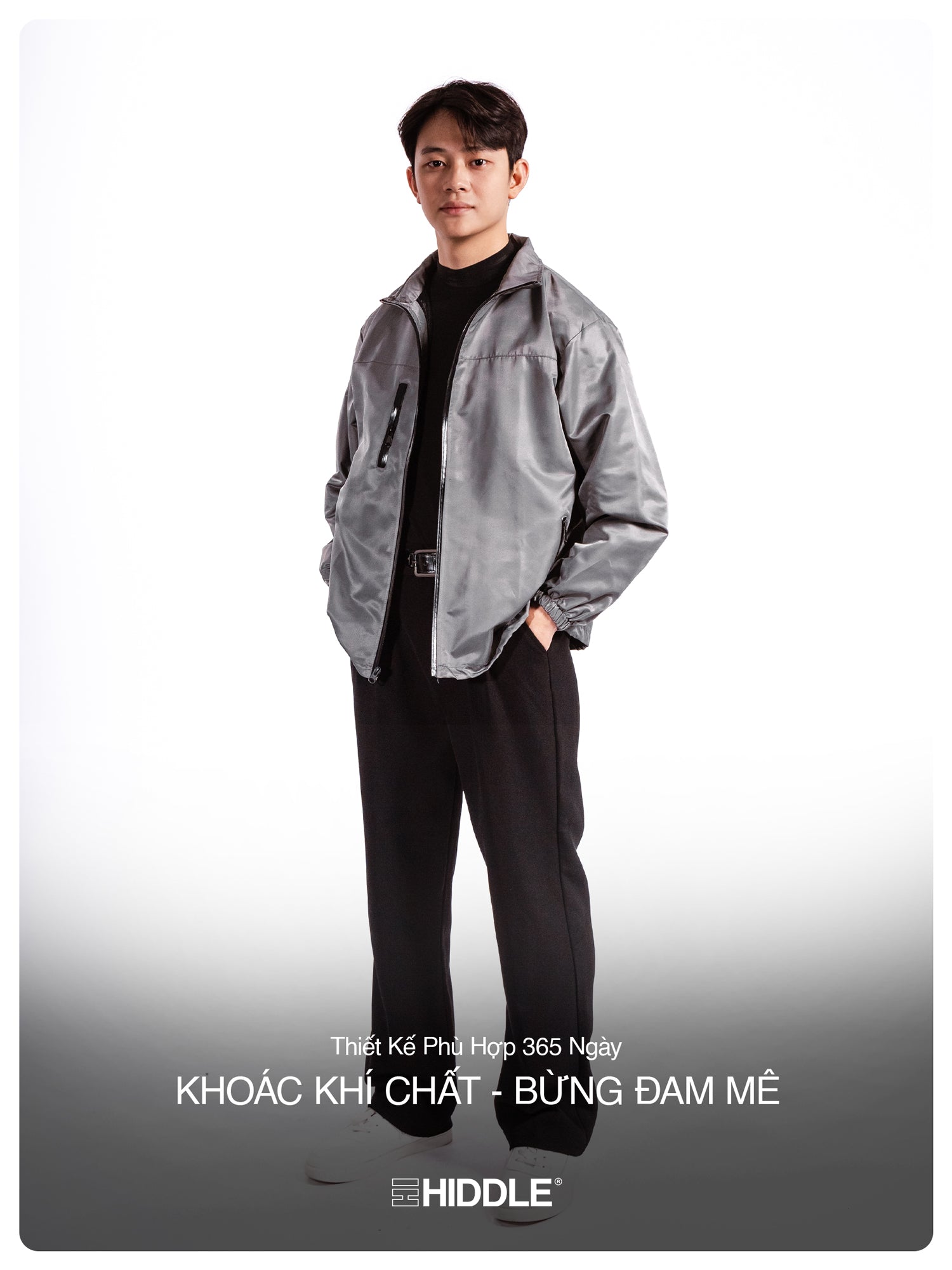 Person wearing a gray jacket and black pants with Hiddle branding on a white background