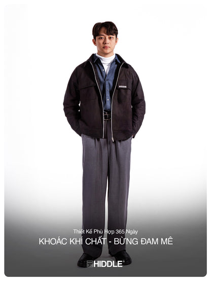 Man wearing a dark jacket and gray pants on a white background with text.