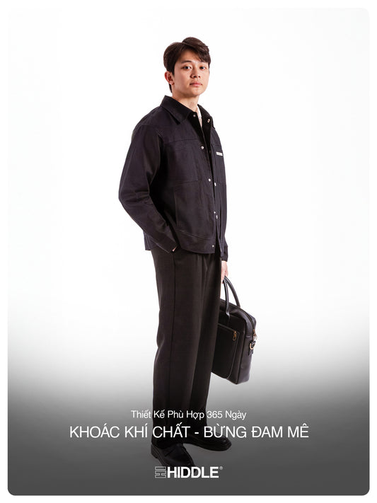 Man wearing a black outfit with a briefcase, standing against a white background, featuring the brand 'Hiddle'.