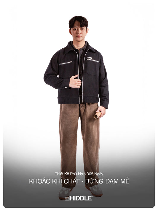 Person wearing a black jacket and brown pants on a white background