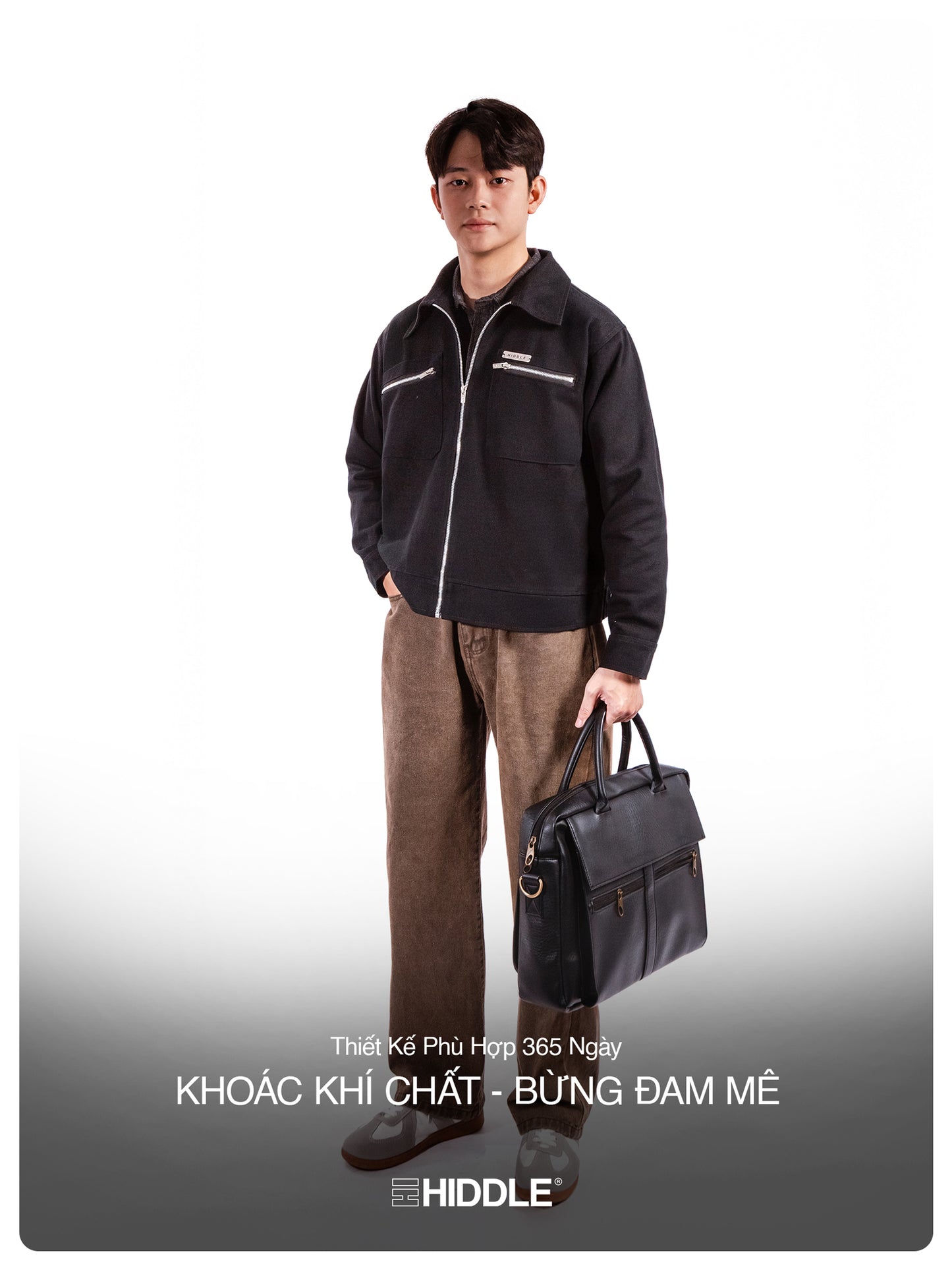 Man wearing a black jacket and brown pants holding a black briefcase on a white background