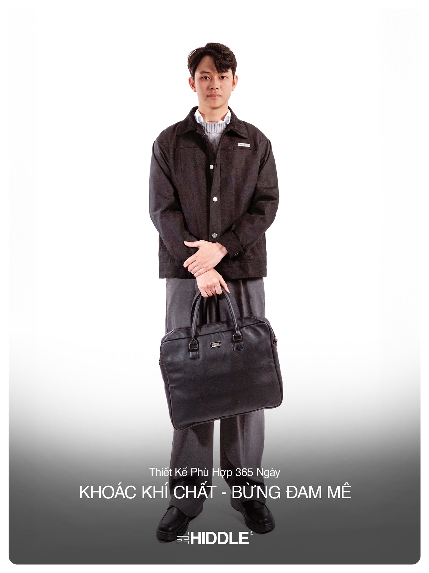 Man holding a black briefcase wearing a dark jacket and pants on a white background