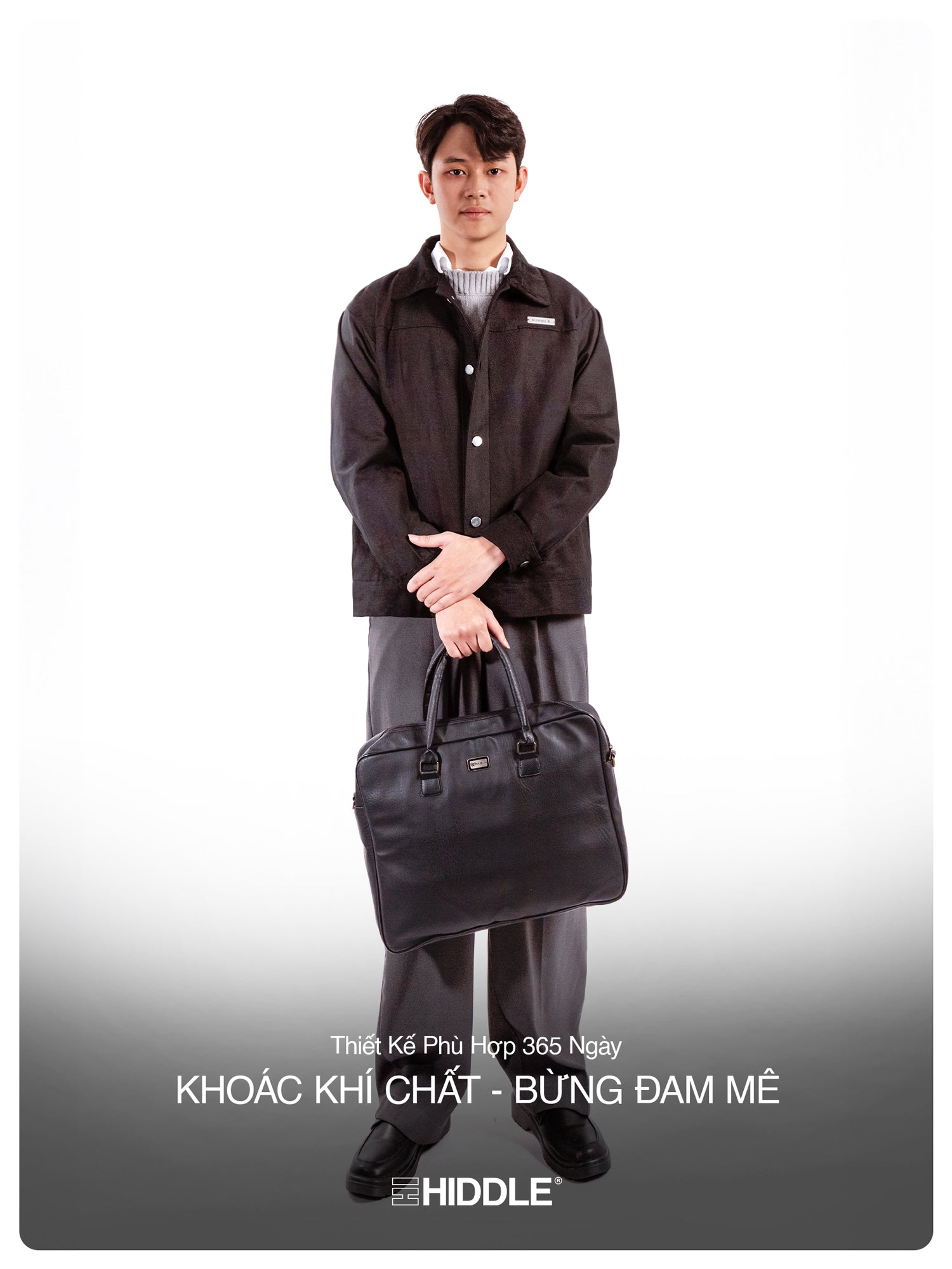 Man holding a black briefcase wearing a dark jacket and pants on a white background