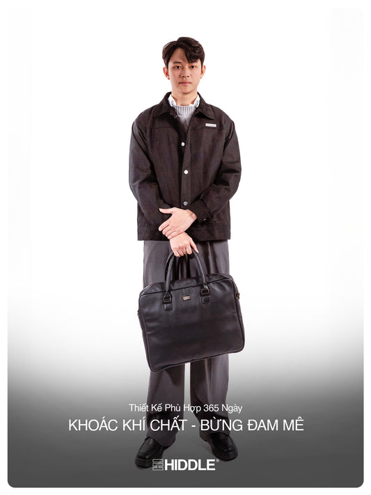 Man holding a black briefcase wearing a dark jacket and pants on a white background