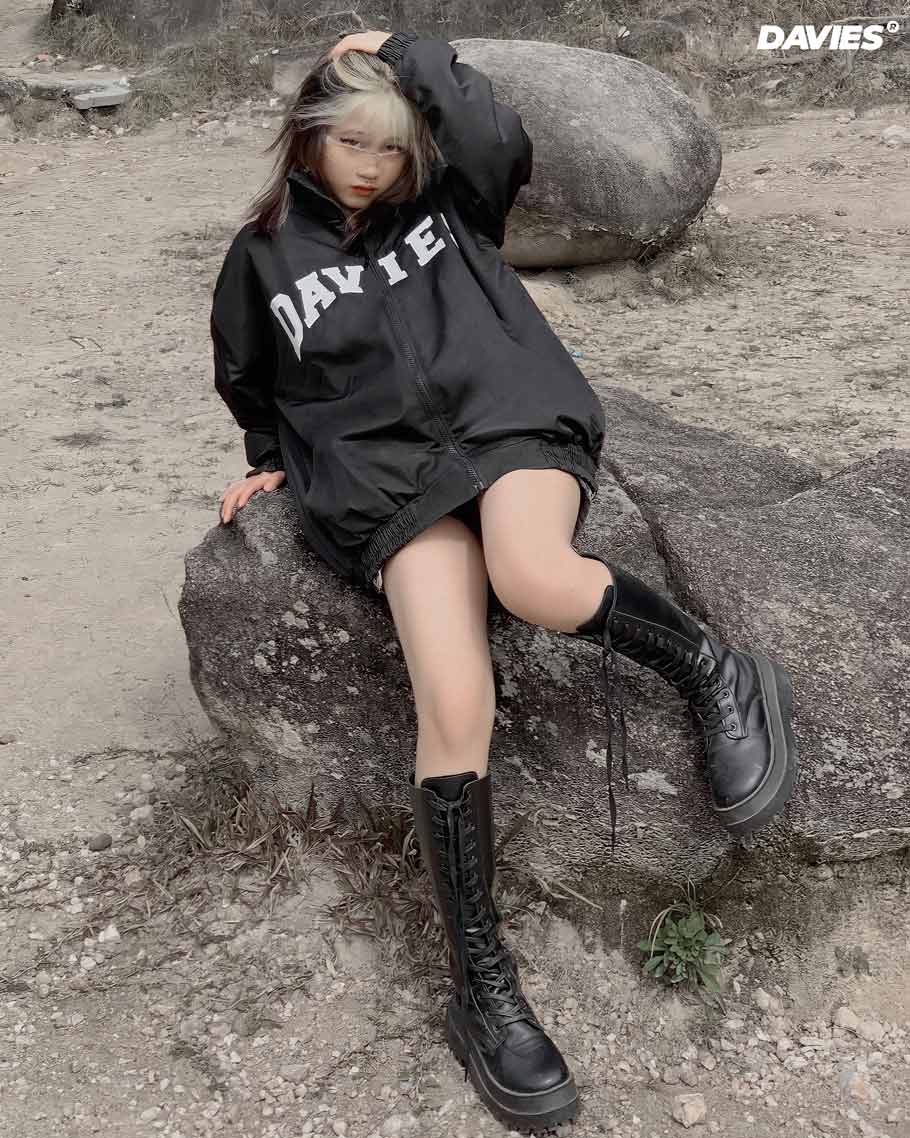 Person wearing a black hoodie with 'DAVIES' branding, sitting on rocks outdoors.
