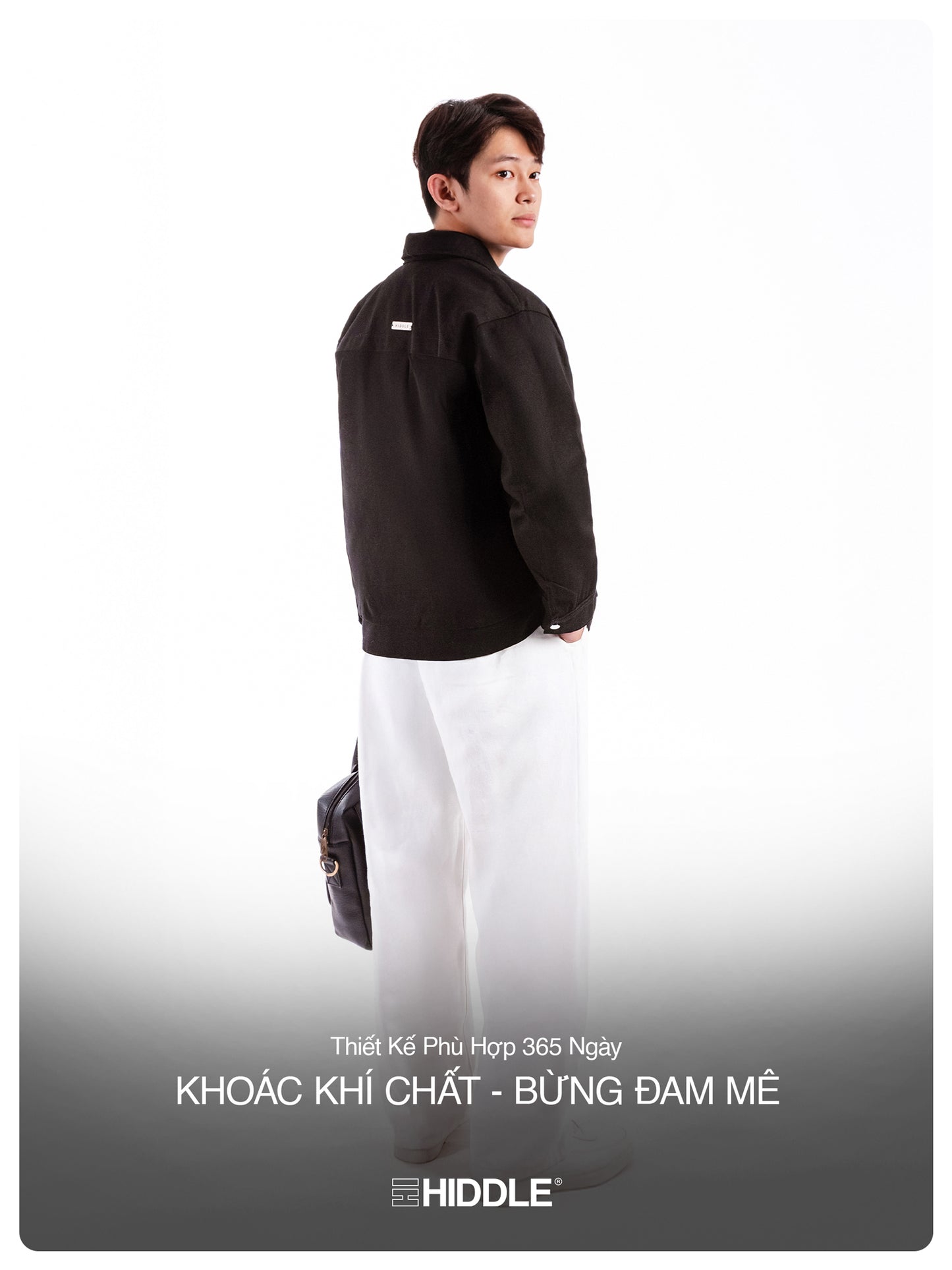 Person wearing a black jacket and white pants with a gray background