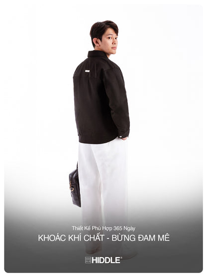 Person wearing a black jacket and white pants with a gray background