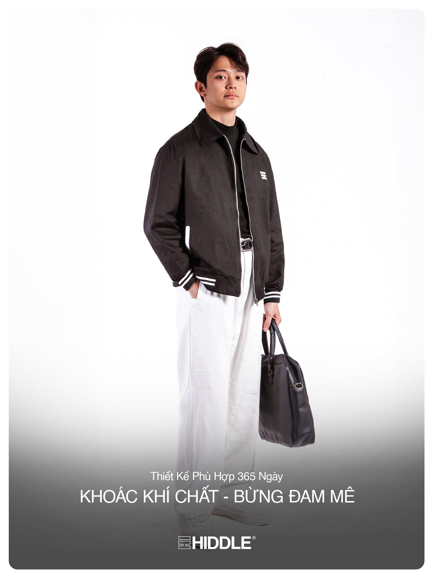 Man wearing a black jacket holding a bag with Hiddle branding on a white background