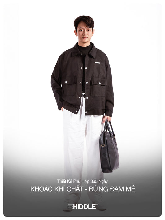Man wearing a black jacket holding a bag on a white background with Hiddle branding.