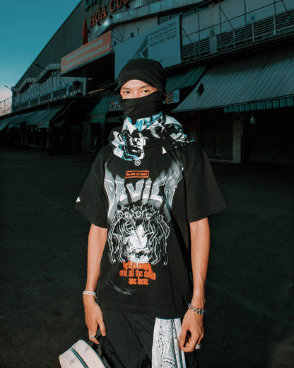 Person wearing a black graphic t-shirt and headscarf in an urban setting