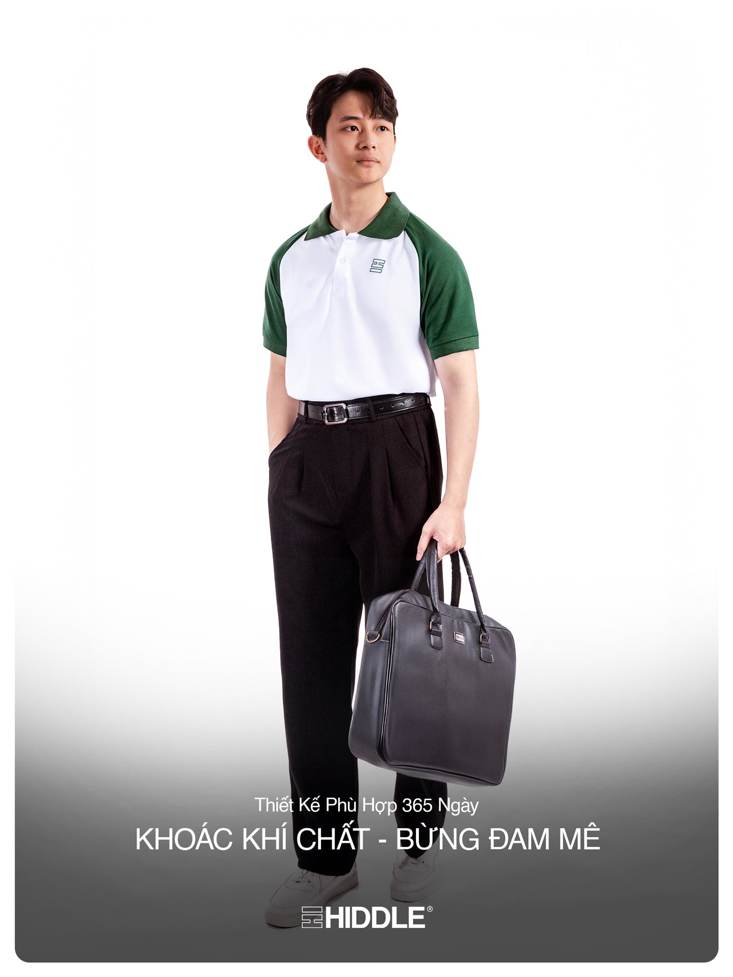 Man holding a gray bag wearing a green and white shirt with black pants on a white background
