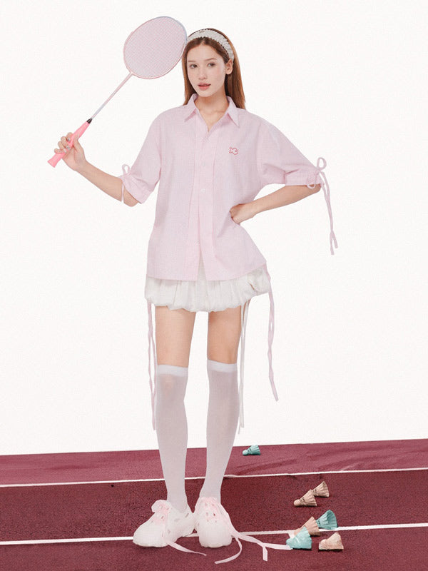 Person in a pink outfit with a white skirt and thigh-high socks, holding a paddle on a red and white surface.