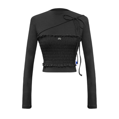 Black long-sleeve top with smocked waist and bow detail on a white background
