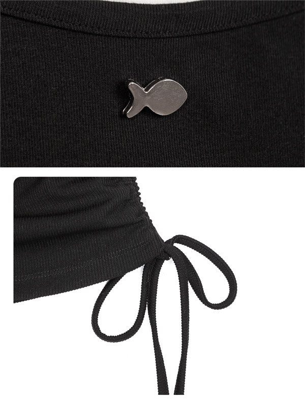 Black top with a fish-shaped brooch and tied waist detail on a white background