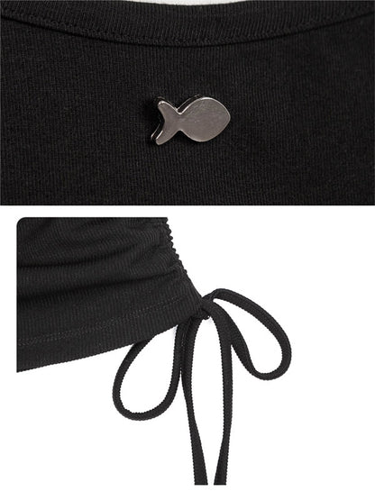 Black top with a fish-shaped brooch and tied waist detail on a white background