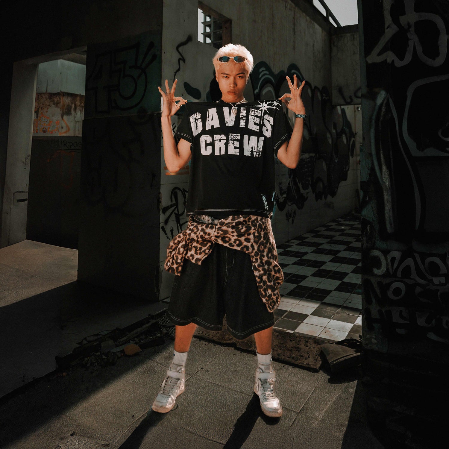 Person wearing a black 'DAVIES CREW' t-shirt in an urban setting with graffiti.