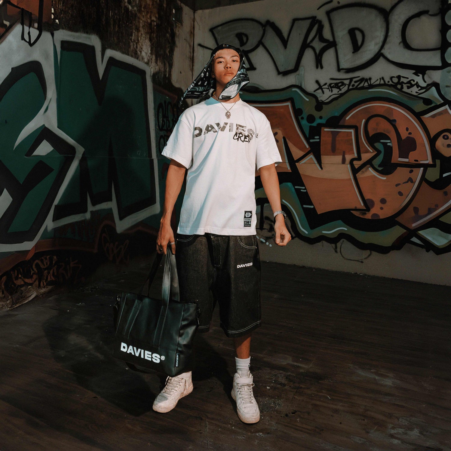 Person holding a Davies bag in front of graffiti wall